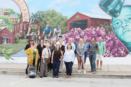 Standing beneath 200 years of local history as they celebrate the Greencastle bicentennial are (front from left) Alexandra Chamberlain with newborn Theo in tow, Jinsie Bingham, Kristin Fuhs Wells, Misti Scott, (middle) Veronica Pejril, Kate Knaul, Laura Monnett, Sue Murray, Larry Tippin, Sarah Podzielinski, Chris Flegal, (back) Phil Asbell, Suzanne Hassler, muralist Damien Mitchell, Mayor Bill Dory, Ken Heeke and Mike Harmless. Banner Graphic/JARED JERNAGAN