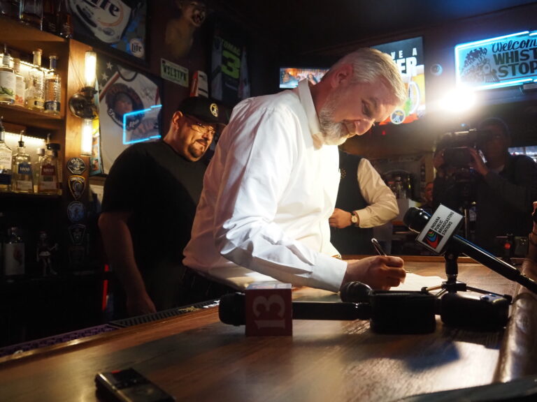  Indiana Gov. Eric Holcomb signs a happy hour bill into law at the Whistle Stop Inn in Indianapolis, Indiana on March 14, 2024. (Leslie Bonilla Muñiz/Indiana Capital Chronicle)
