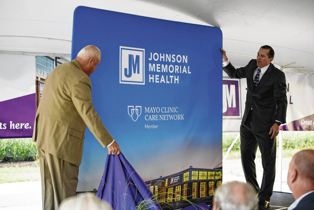 Dr. David Dunkle, president and CEO of Johnson Memorial Health, right, and R. Martin Umbarger, chairperson of the Johnson Memorial Health board of trustees, unveils a banner touting the hospital’s collaboration with Mayo Clinic during an event on Aug. 31, 2022, at the Franklin hospital. Daily Journal File Photo