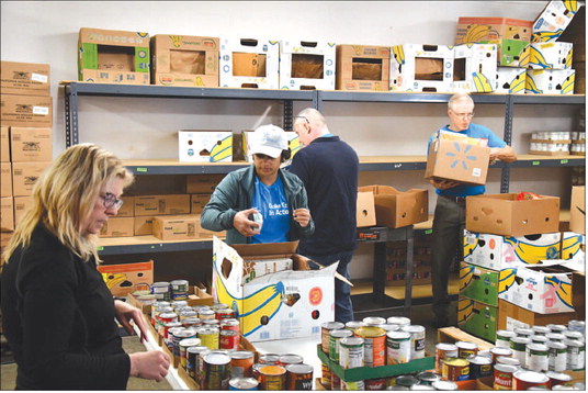 Duke Energy employees helped organize and restock the shelves at The Center for Lay Ministries to help the organization easily give food to those who need it. Photo by Erik Hackman | News and Tribune