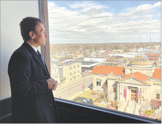 Mariusz Kurylo, former owner of the Anderson Executive Tower, takes in the view from a north-facing window on the building’s seventh floor in this 2022 file photo. Kurylo recently sold the building to Noblesville-based investors Sid Mahant and Mahesh Goel, who envision continuing to have office space available while developing the upper floors into apartments. File photo | The Herald Bulletin