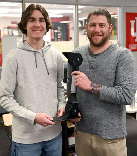Terre Haute South student Bryce Norris and design technology teacher Daniel Card display the prosthetic leg that includes the foot created by Norris with a 3-D printer attached to it on Thursday at the school. Staff photo by Joseph C. Garza