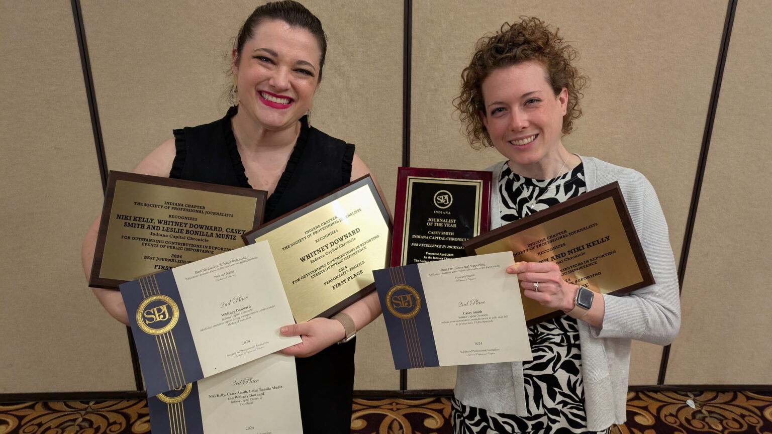 Senior Reporters Whitney Downard, left, and Casey Smith hold the Indiana Capital Chronicle’s seven awards following a Society of Professional Journalists banquet on May 2, 2025. (Submitted photo)