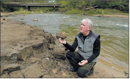 Since the removal of Markle Mill Dam in October of 2023, Brendan Kearns, director of the Vigo County Soil and Water Conservation District, has found that the health of the creek and the fish in it near the old dam site have improved. Here, Kearns kneels next to the creek April 30 and points out adjacent clay material that he said could be from sediment that came downstream 200 years ago at the creek near Markle Mill Park. Tribune-Star/Joseph C. Garza