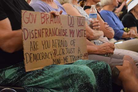 Opponents hold a sign against an early redistricting at the Indiana Statehouse on Aug. 7, 2025. (Casey Smith/Indiana Capital Chronicle)