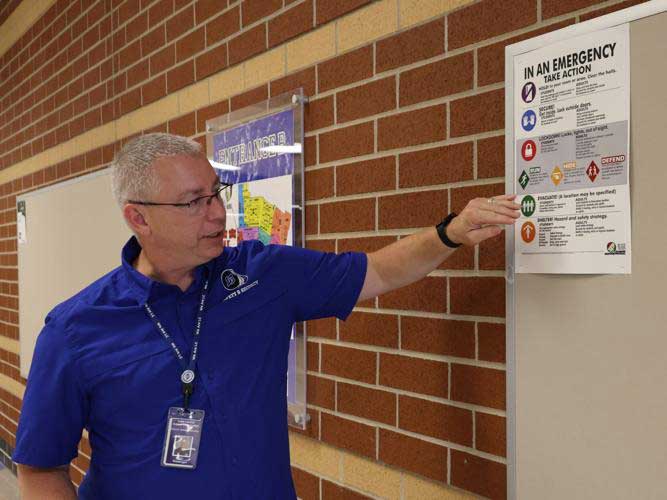 Director of Safety and Security Brian Kissinger points out the safety protocols on one of the many posters at Lake Central High School and other schools in the district. Staff photo by John J. Watkins
