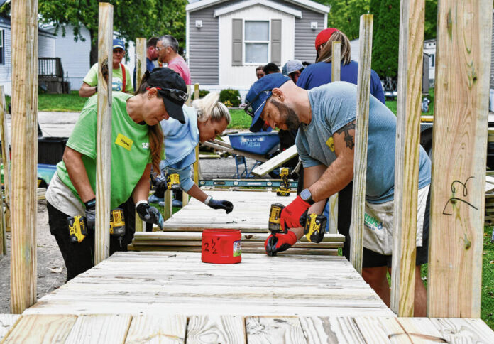Employees from Rehab Medical, a medical equipment company headquartered in Indianapolis, volunteer with Servants at Work on a ramp for a family in Greenwood on Wednesday. The completed ramp, which was needed to help the family get their 6-year-old son in and out of the house safely, was the 5,000th project for Servants at Work. RYAN TRARES | DAILY JOURNAL