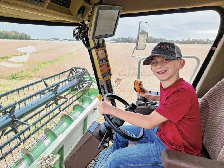 Ten-year-old Dean Thompson drives the combine on his family’s farm, with a little help from his dad. Submitted photo