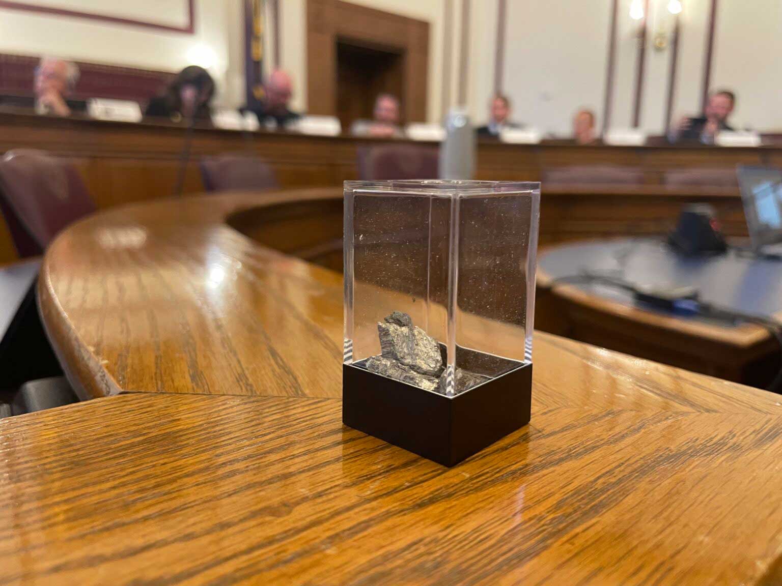 A container with 10 grams of yttrium, a rare earth element, is passed around during a meeting of the Indiana Rare Earth Recovery Council on Nov. 13, 2025. (Photo by Leslie Bonilla Muñiz/Indiana Capital Chronicle)