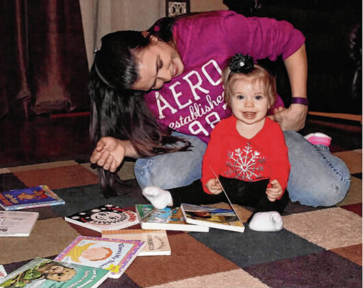 Kendra Ball reads a book provided by the Imagination Library to daughter Kayla in this 2017 photo. Kayla Ball was the first child enrolled in Hancock County’s Imagination Library after its 2015 launch. Daily Reporter file photo