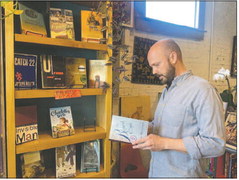 Mickey Ball, owner of Mickey’s in New Albany, pulls Toni Morrison’s “The Bluest Eye” from the shelves of the bookstore’s Banned Books Week display on Sept. 21. The collection included many classic books. Brooke McAfee | News and Tribune